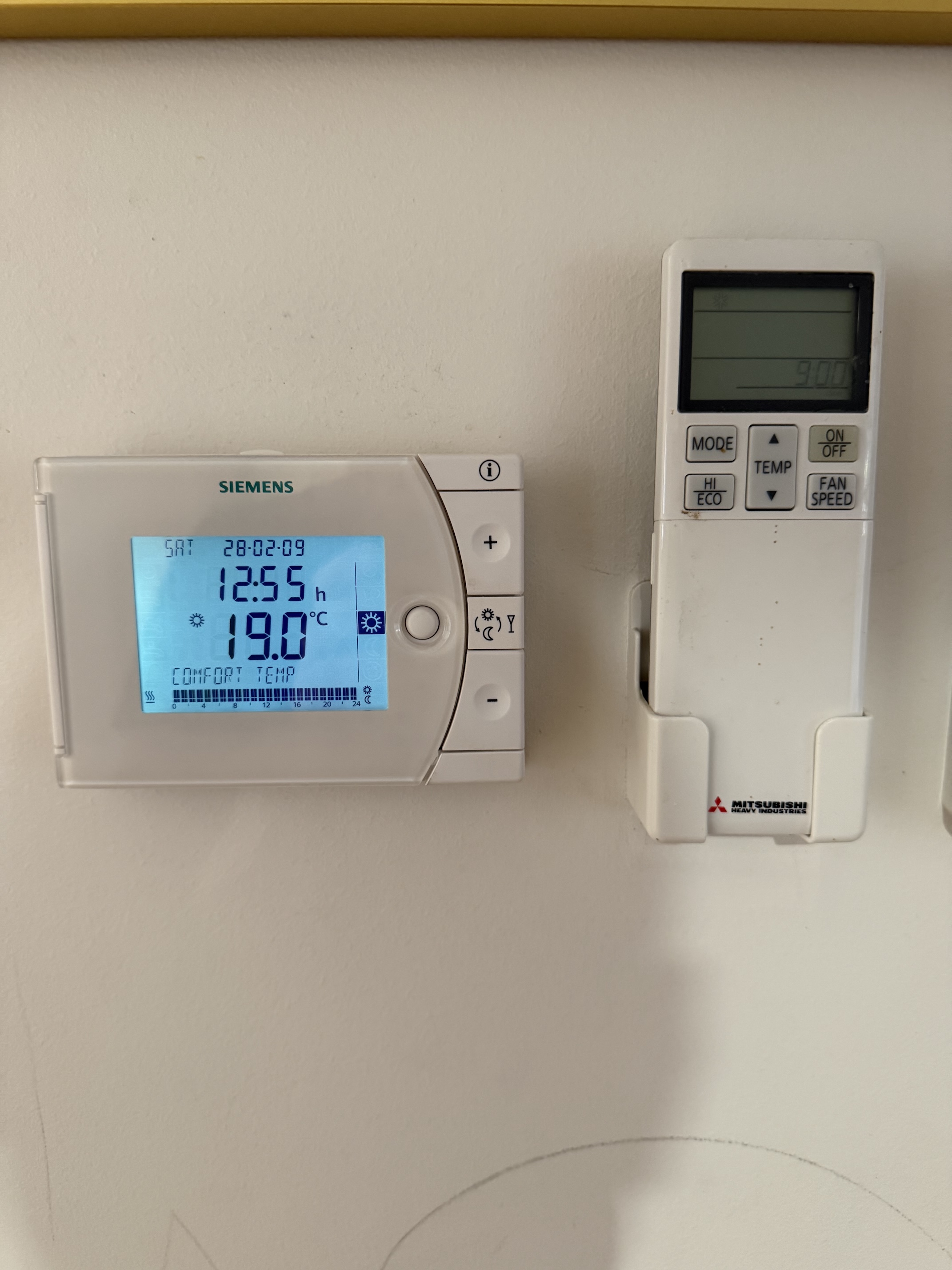Siemens heating panel beside a Mitsubishi air conditioner remote